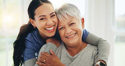 Lächelnde Pflegerin umarmt eine Seniorin Lächelnde Pflegerin umarmt eine Seniorin